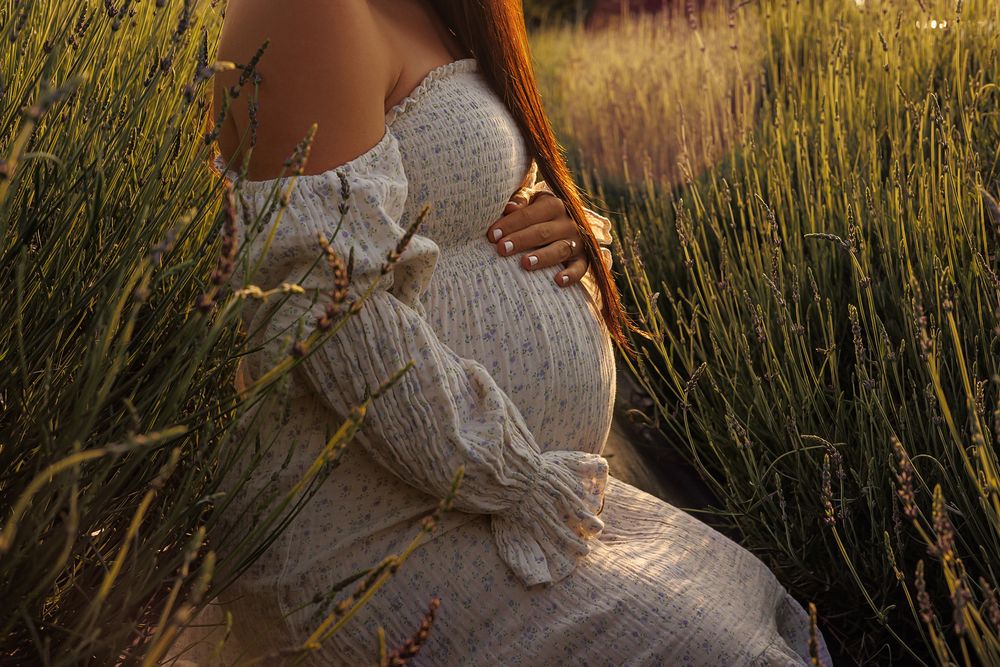 Ethereal maternity photo showing lace dress details in golden sunlight.