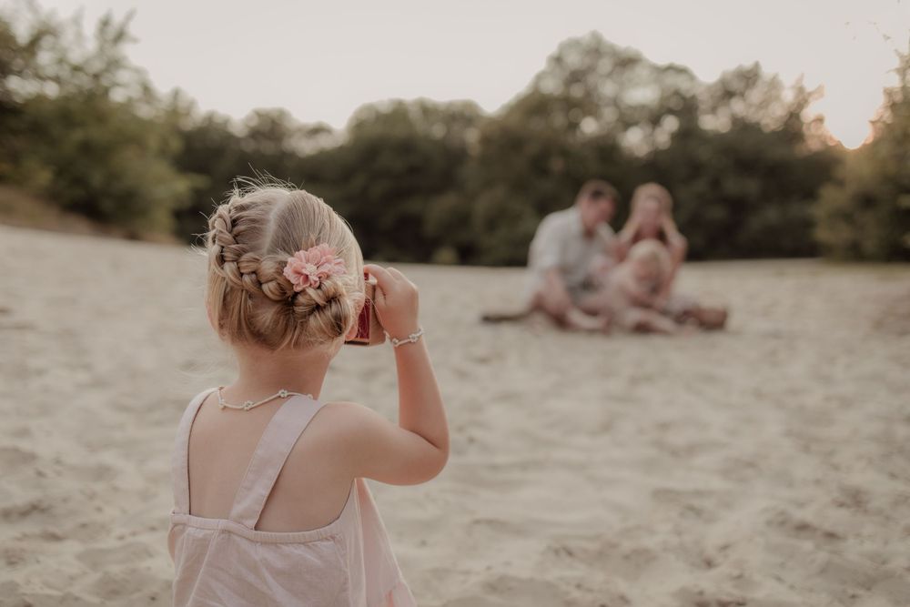 Meisje met bloemen in haar haren neemt een foto tijdens een goldenhour fotoshoot.