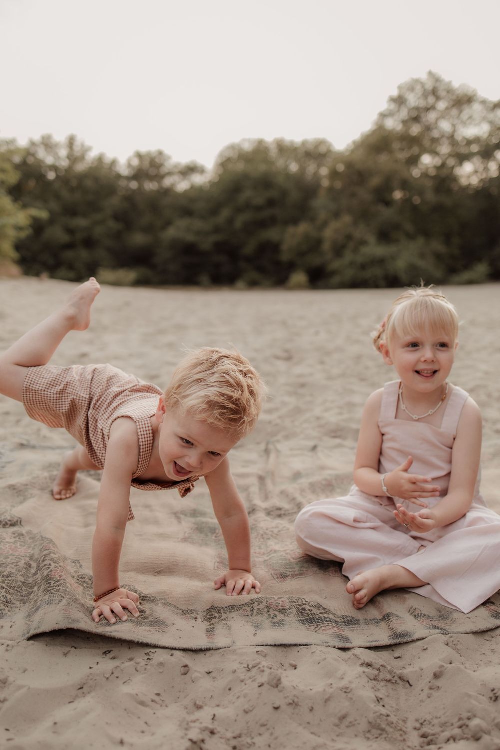 Twee kinderen spelend tijdens de zonsondergang in de duinen.