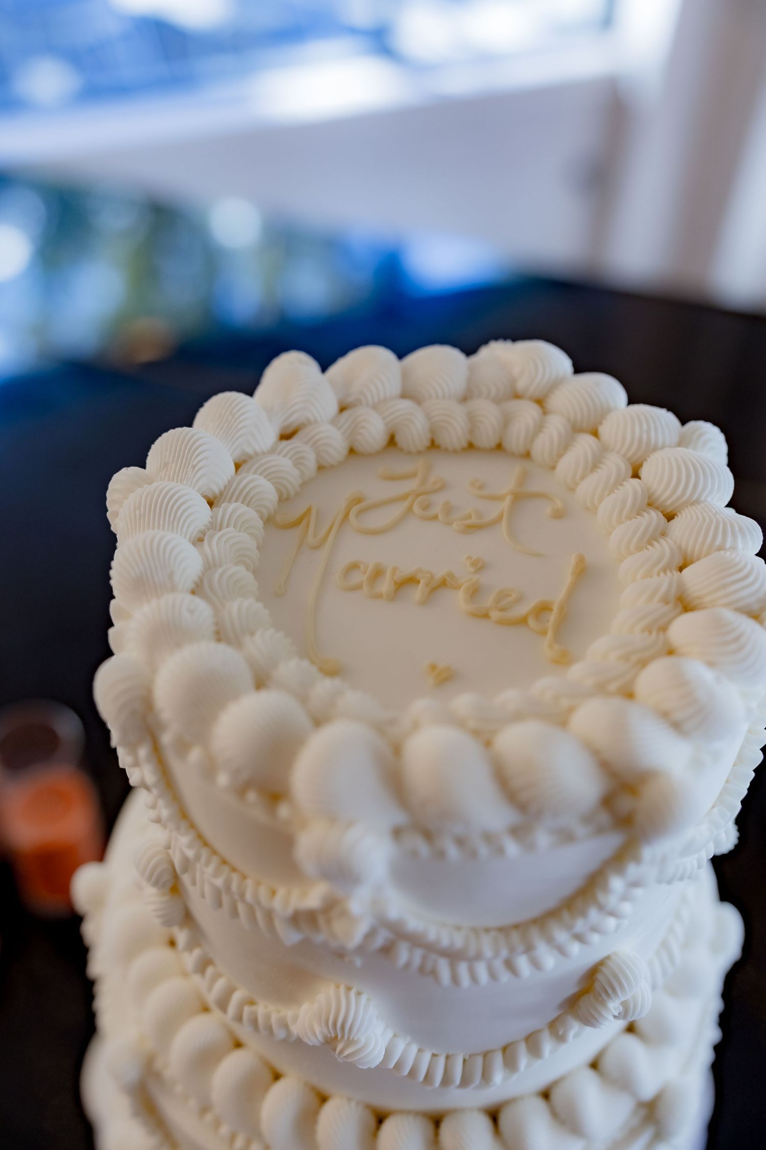 Close-up of white wedding cake with ornate piped details and 'Just Married' text.