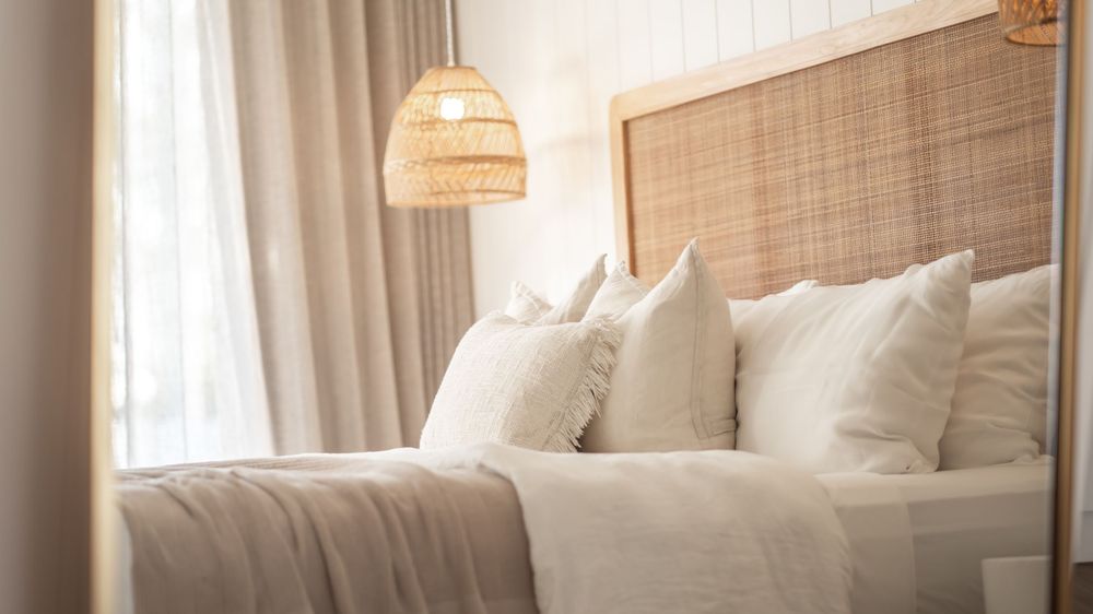Bright bedroom interior with natural rattan accents and soft white linens.