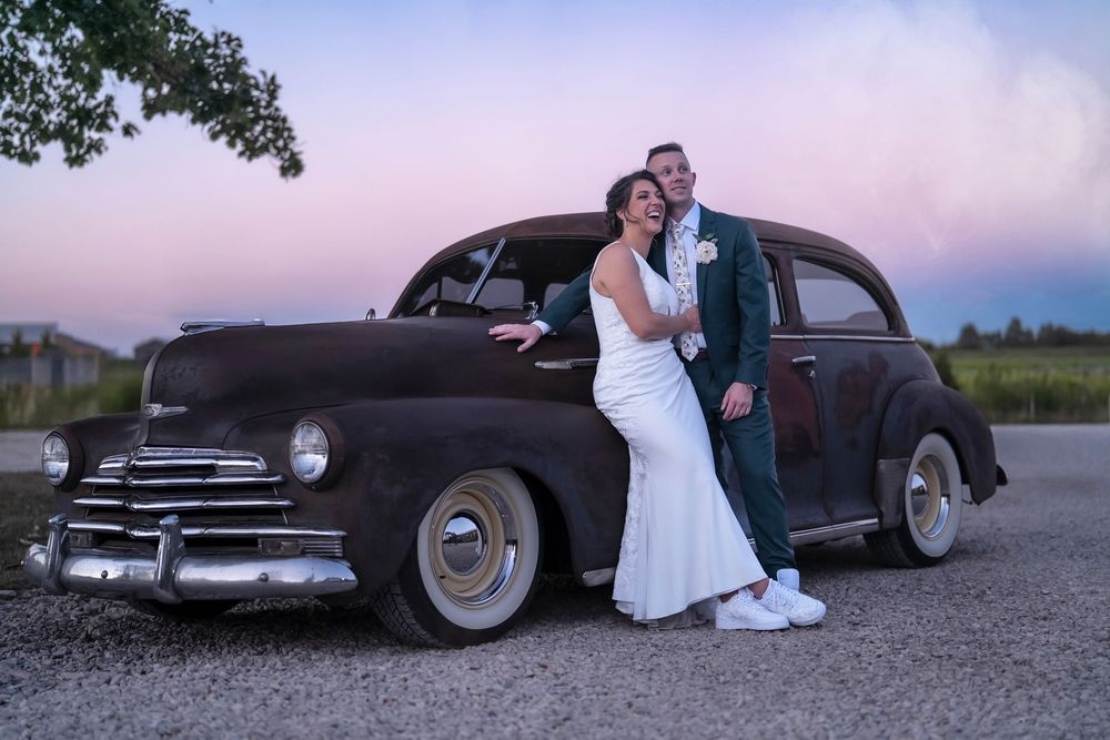 Wedding couple poses with vintage classic cars during sunset photoshoot at retreat 21 venue