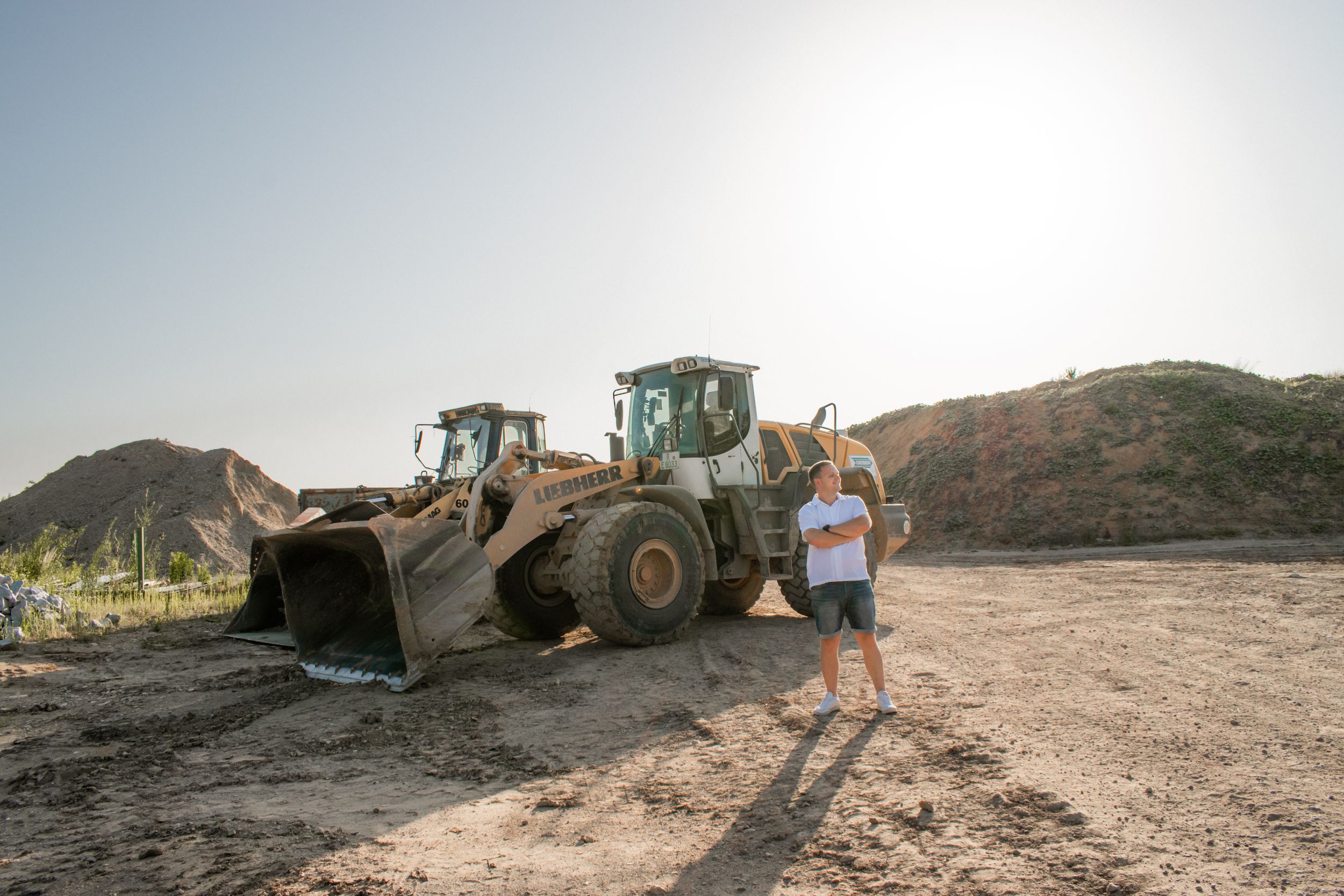 Heavy construction equipment operates near a hillside during an excavation and earthmoving project.