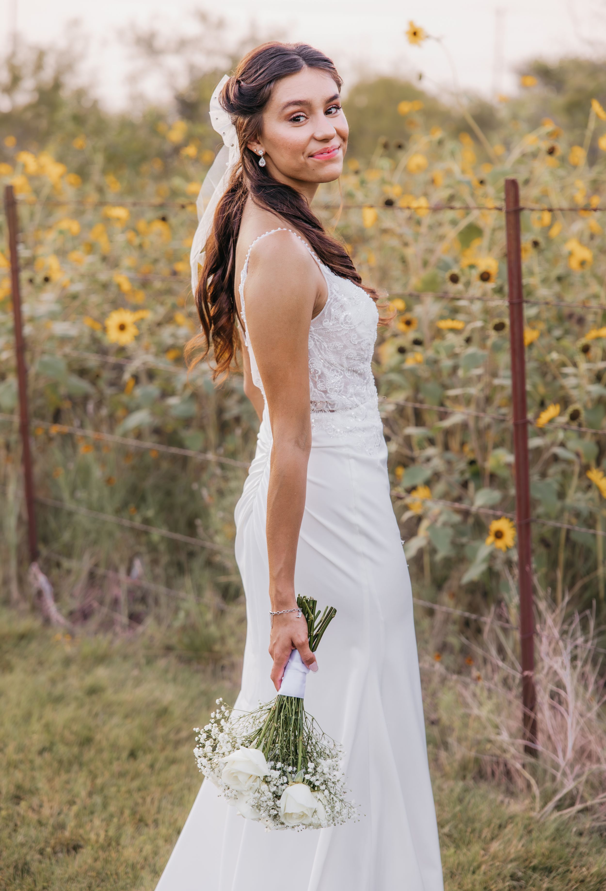 Bride standing in front of a sunflower field during a summer wedding in Temple, Texas