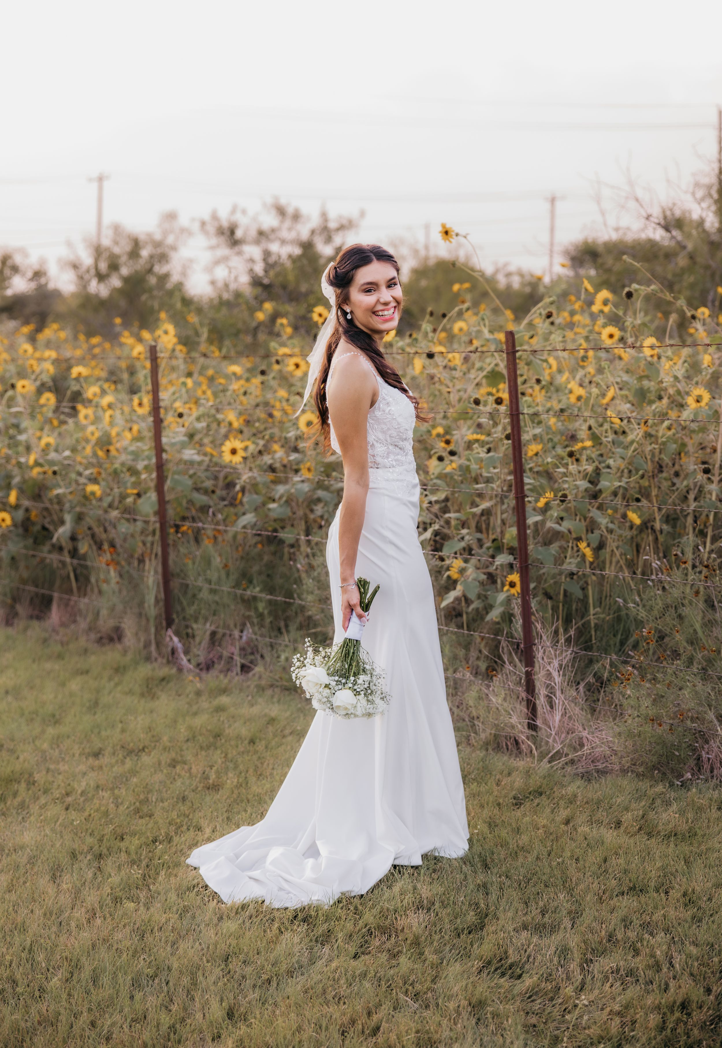 Bride smiling beautifully in front of a sunflower field during a summer wedding in Temple, Texas