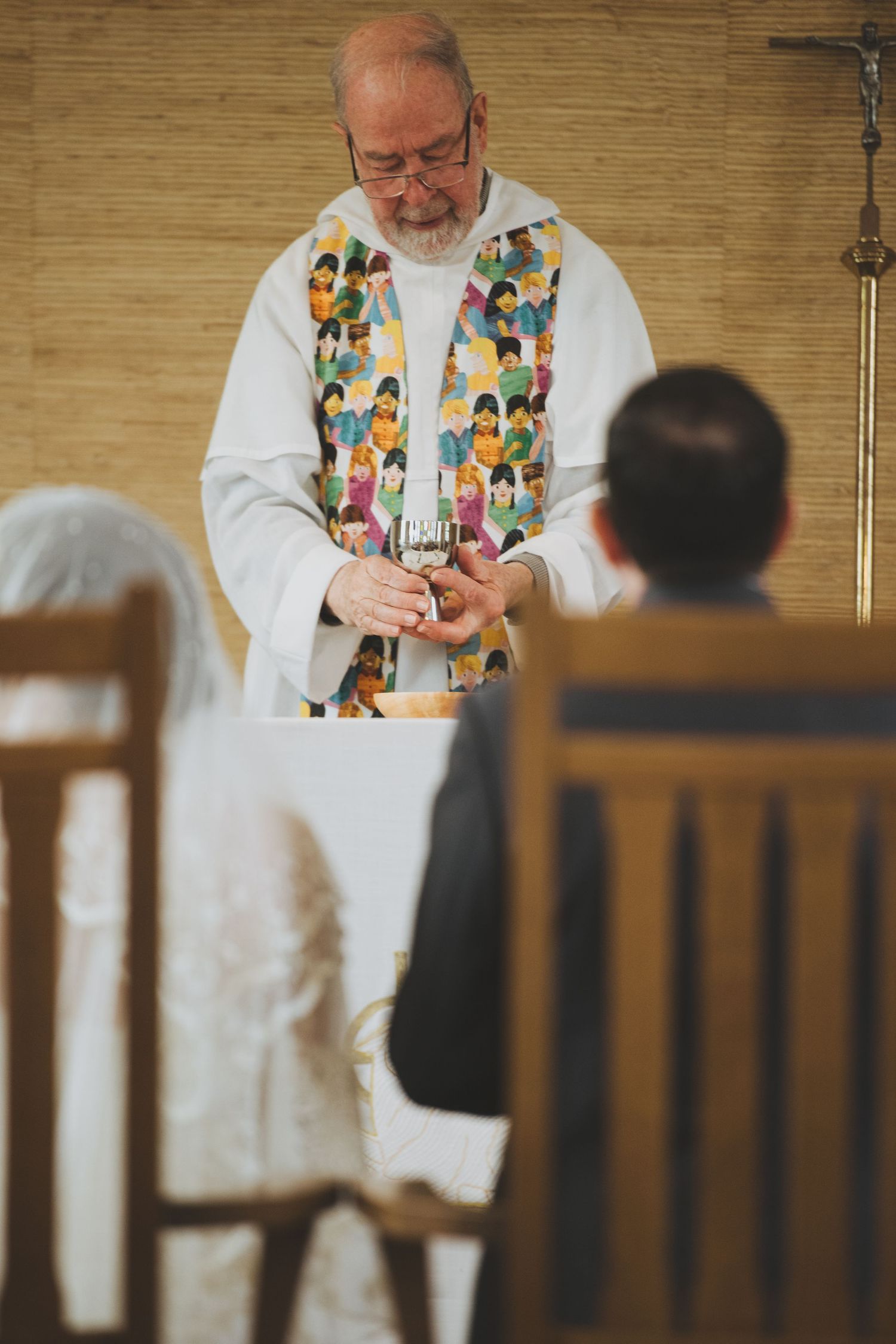 Priest wearing a colorful vestment performs a religious ceremony in church.