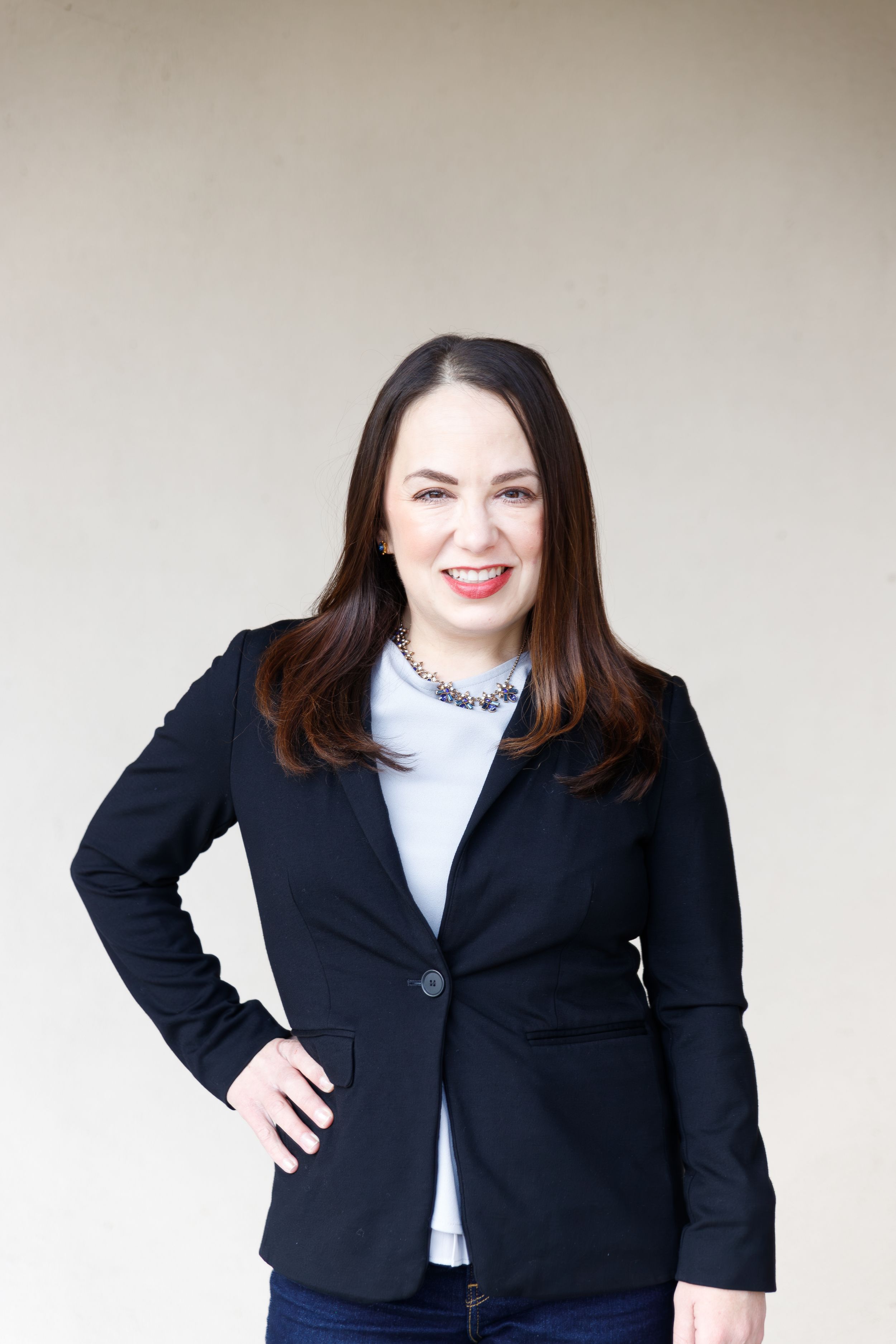 A portrait of someone in professional business attire posing against a neutral background.