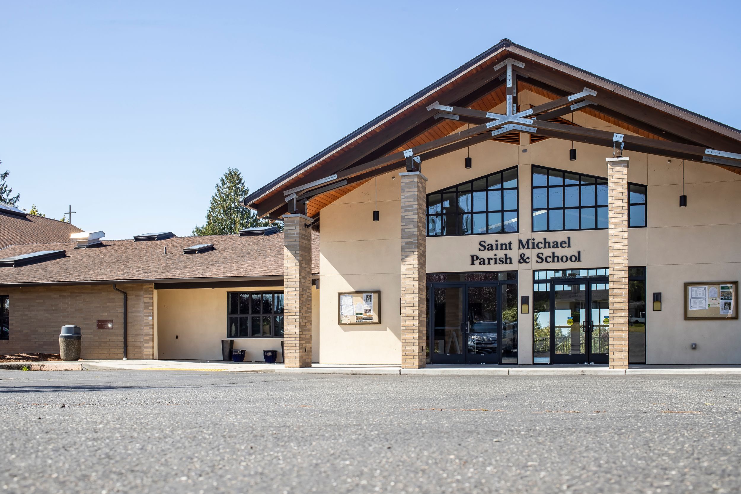 Modern community center building exterior with large glass windows and wooden beams under an angled roof.