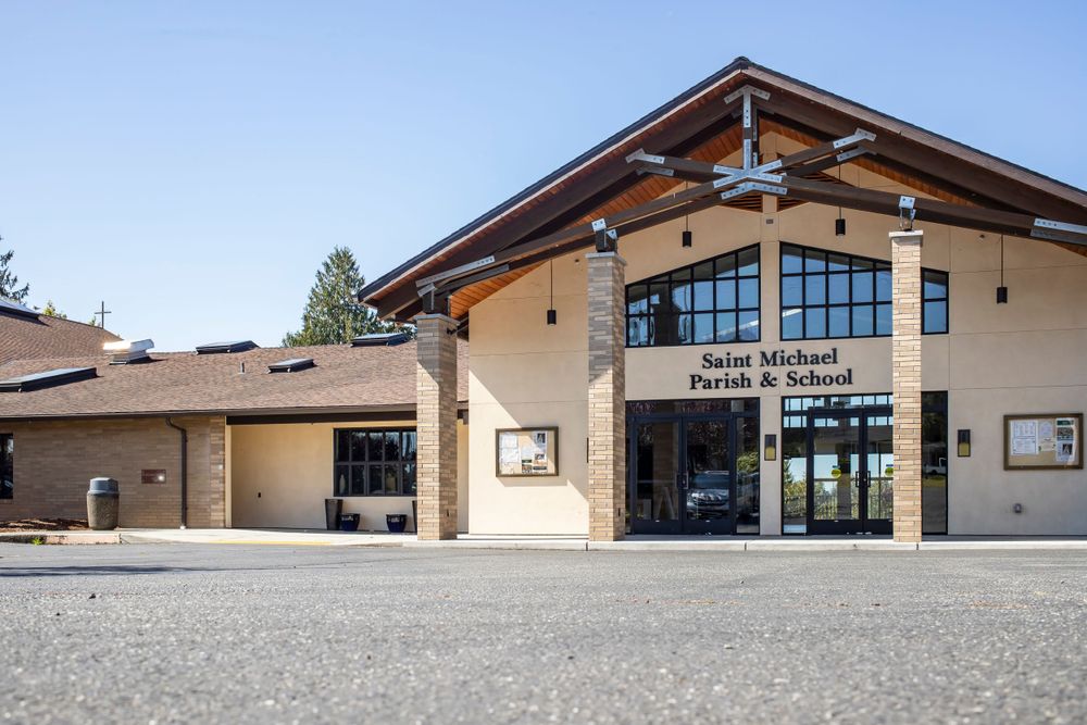 Modern community center building exterior with large glass windows and wooden beams under an angled roof.