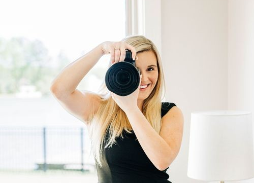 Preslee McGough - Professional Photographer holding DSLR camera while shooting by natural window light.