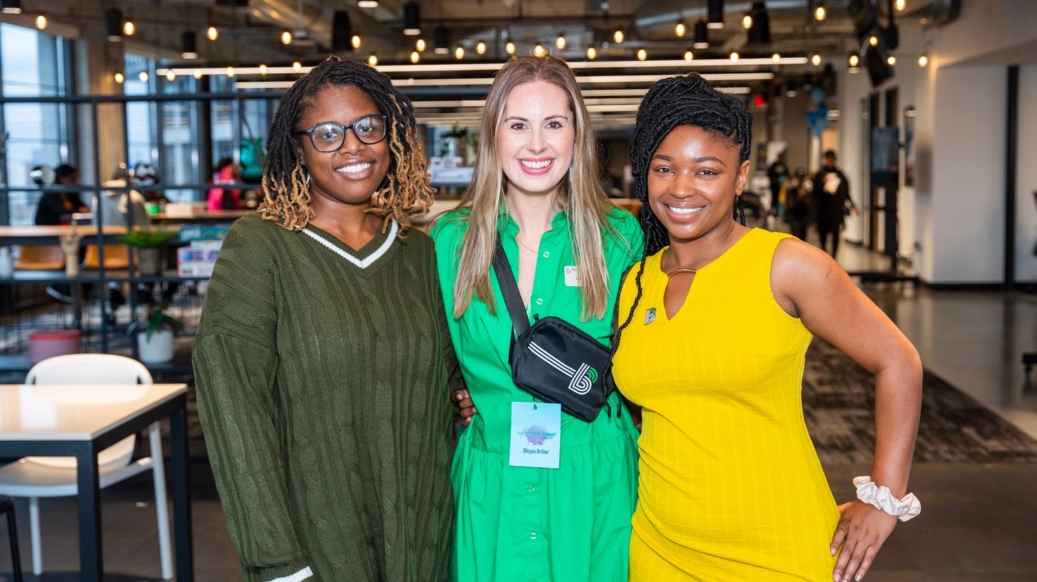 Three professionals gather and smile at a networking event in a modern office space.