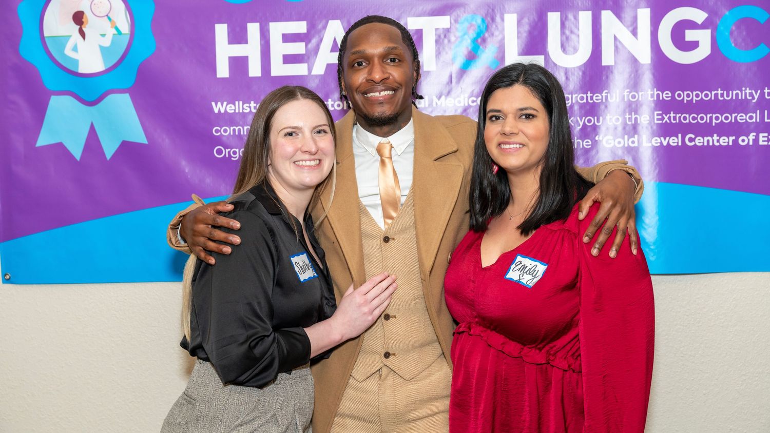 Three people pose together at a Heart Lung medical event with branded backdrop.
