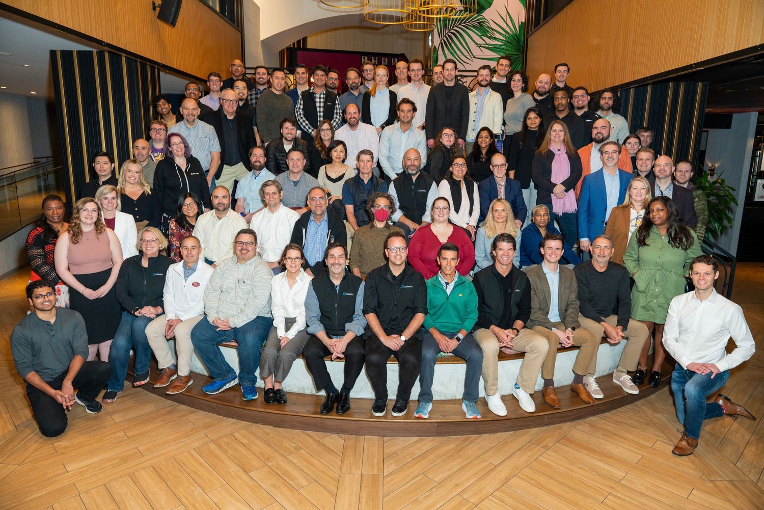 Large group photo of employees gathered on curved steps for a company team picture.