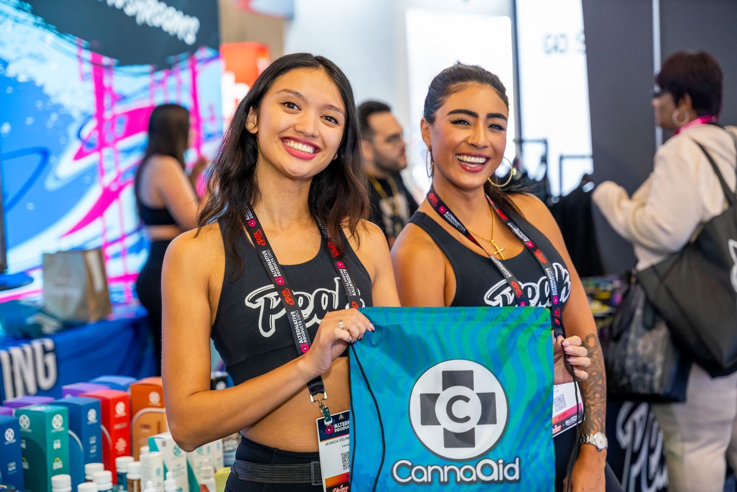 Brand ambassadors in black tops hold turquoise promotional banner at event.