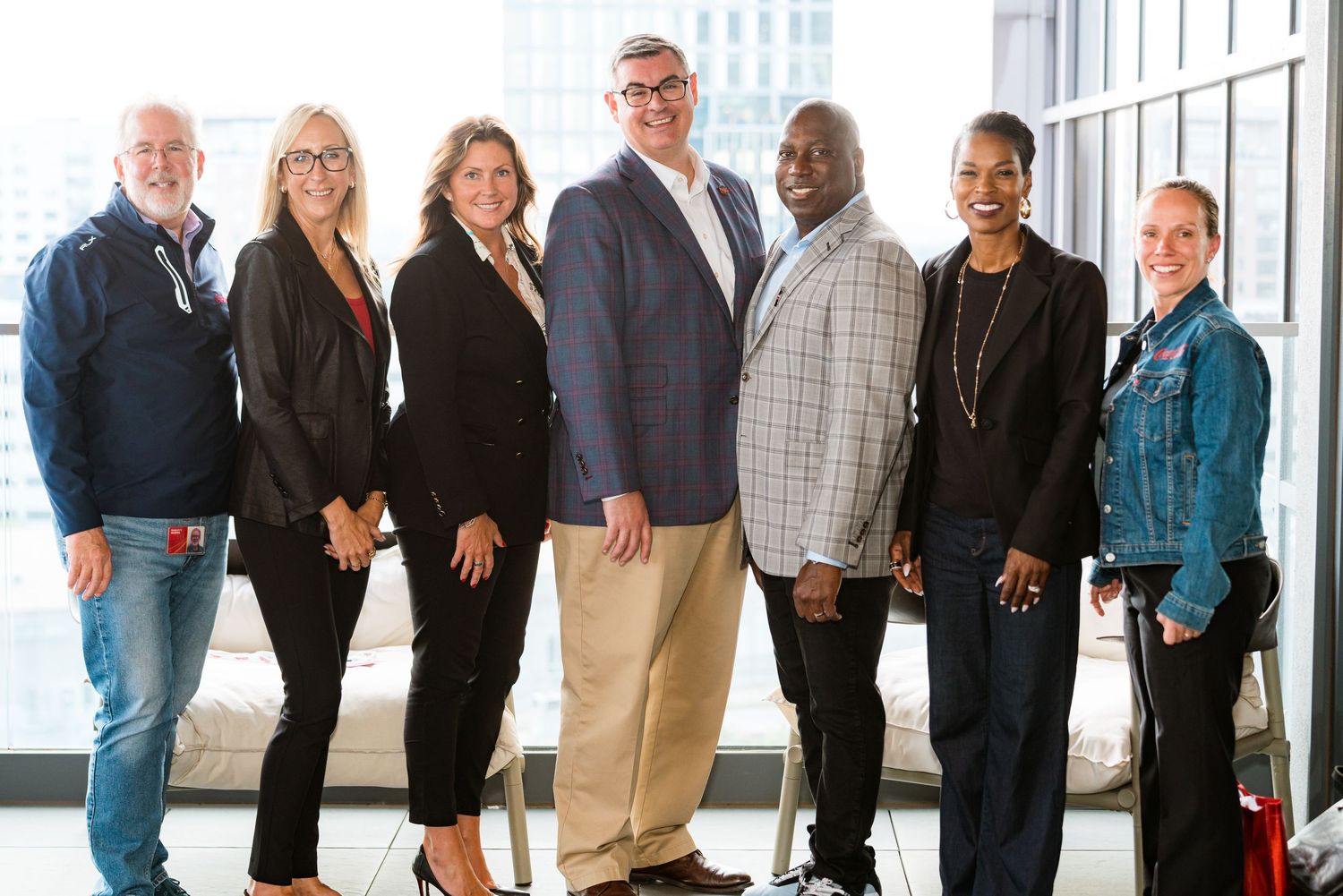 A row of business professionals standing in line against a bright office window.