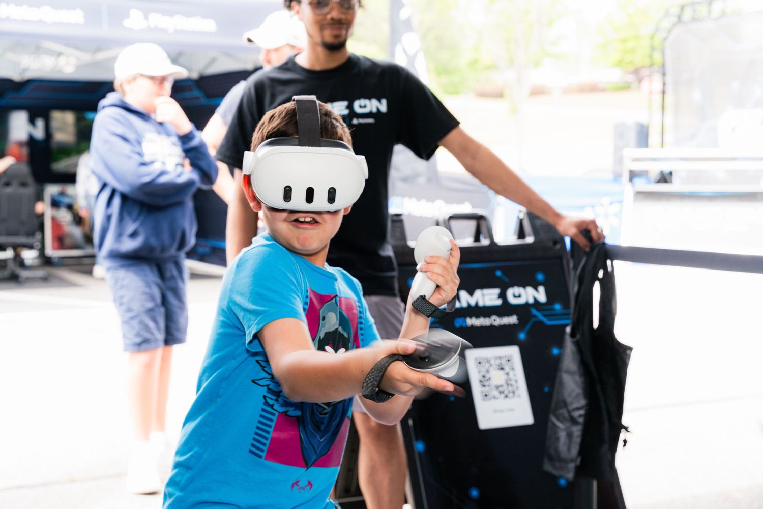 Child wearing VR headset tries virtual reality experience at outdoor event.