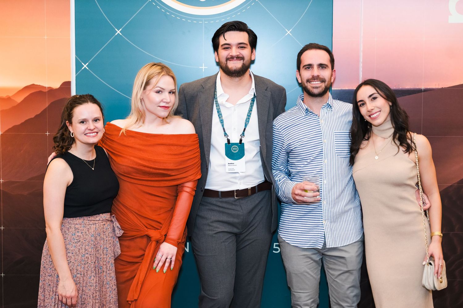 A group of people standing together at a social event with colorful lighting in the background.