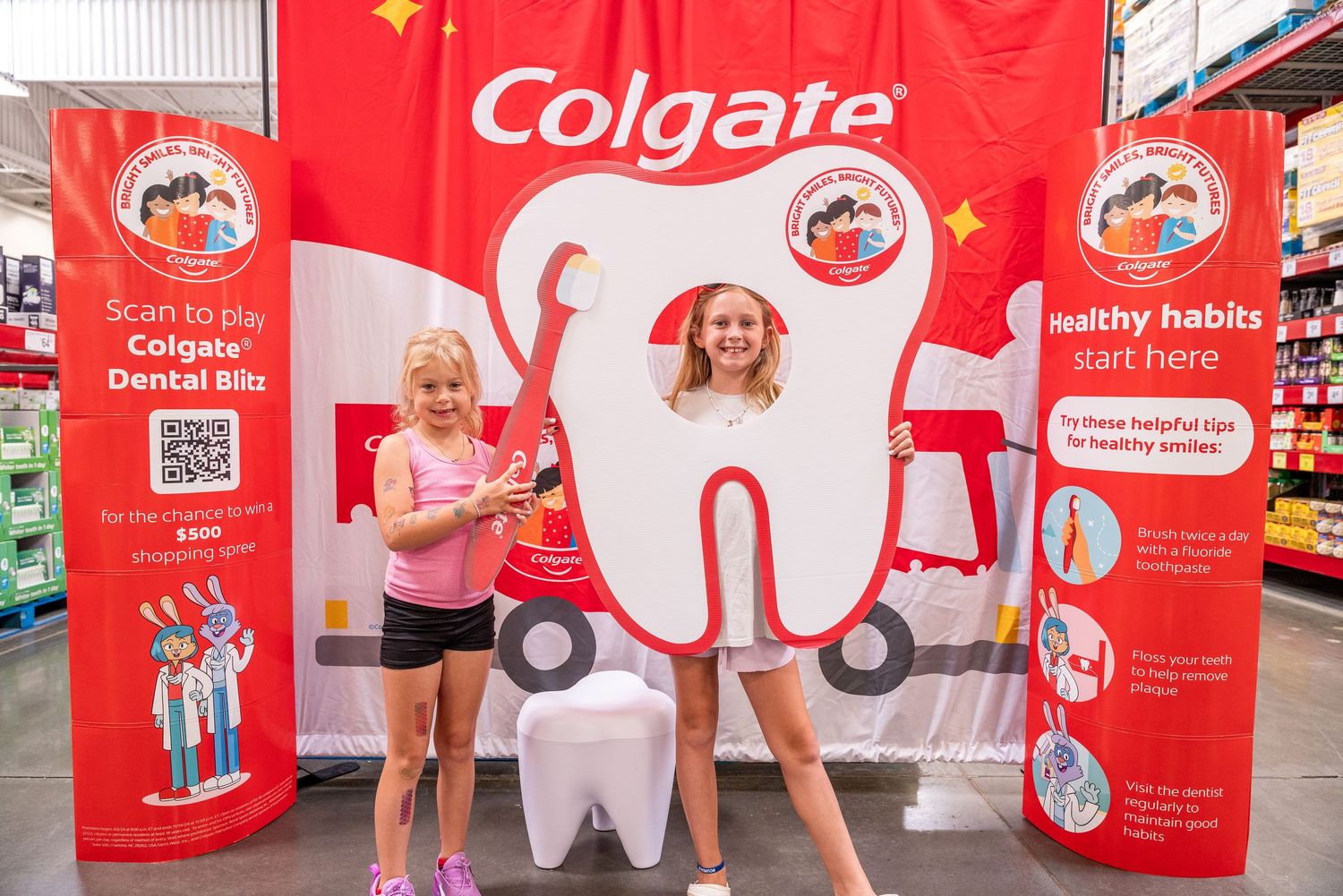 Promotional event setup with Colgate branding and tooth mascot display in retail setting.