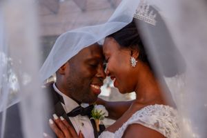 Bride and groom smiling under veil photography
