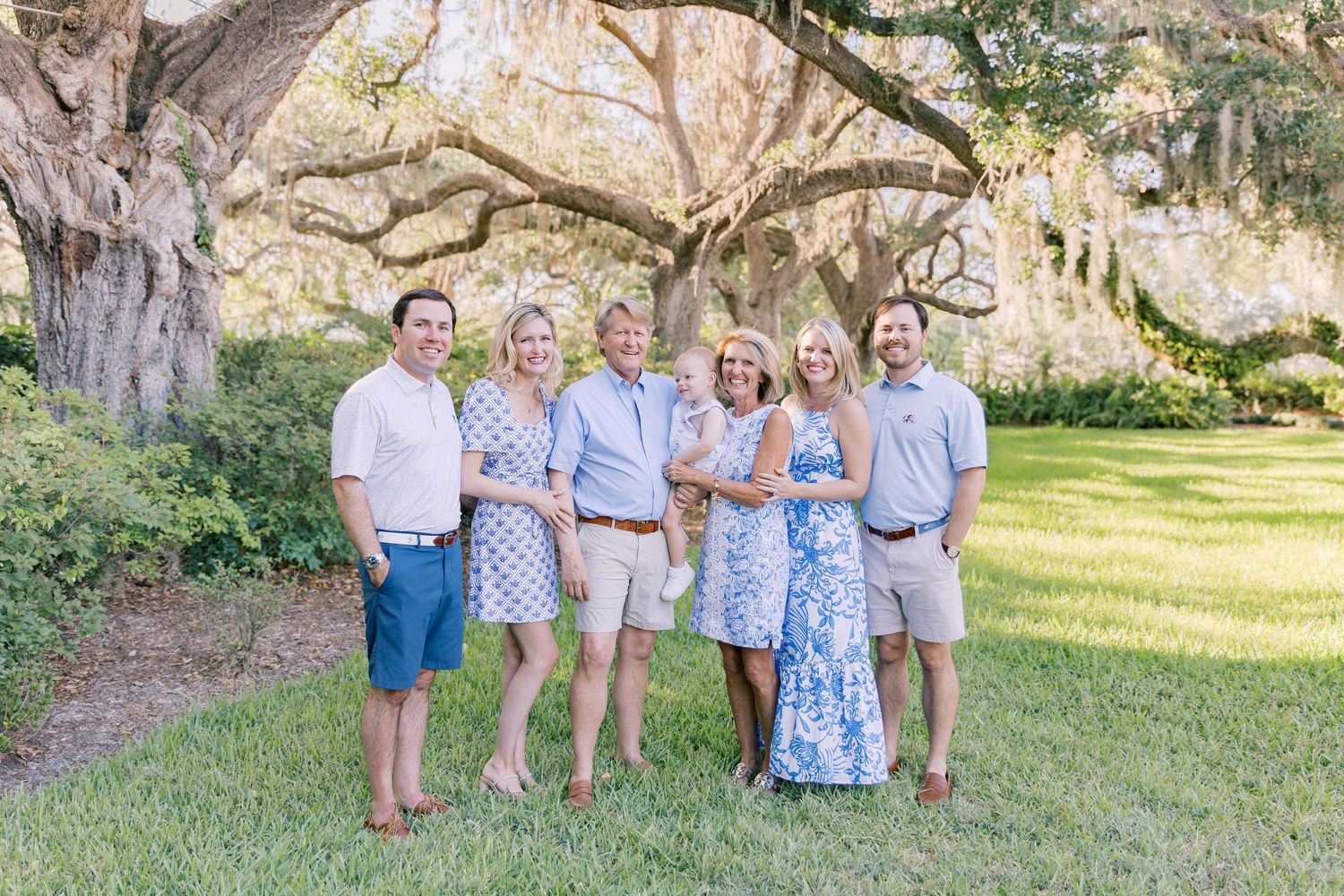 Group portrait of family members standing together under moss-draped oak trees.
