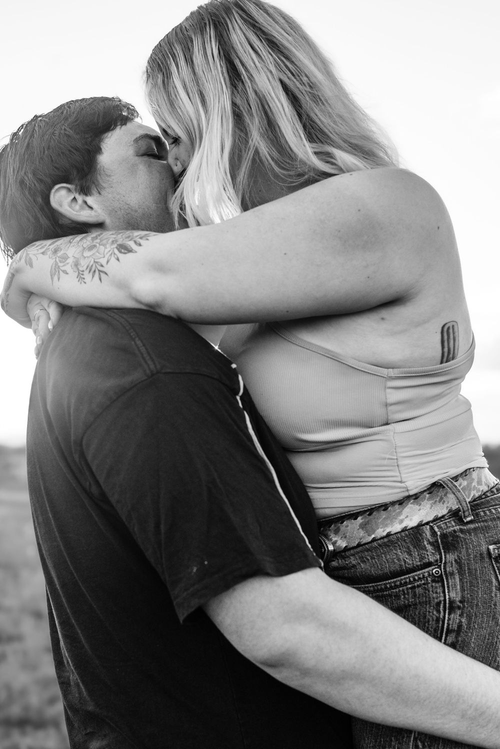 Black and white portrait of an intimate embrace between a couple outdoors.