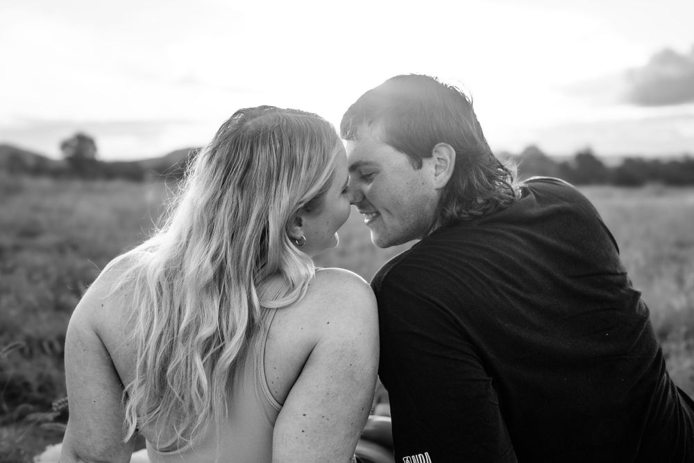 Black and white close-up of a tender moment between a couple in a natural outdoor setting.