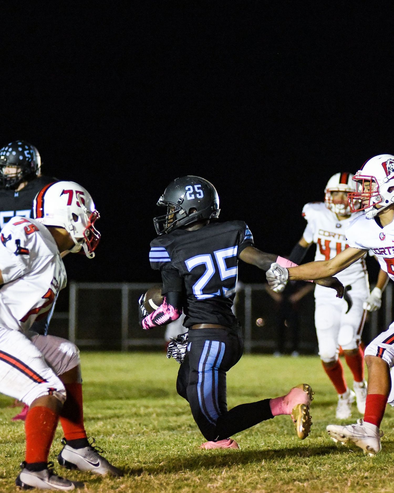 Football players in white and dark blue uniforms competing during a nighttime game.