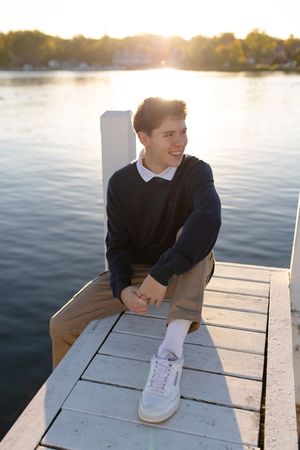 Person in formal attire sitting on white dock during sunset. Senior photo session. Lake Geneva Wisconsin Photographer