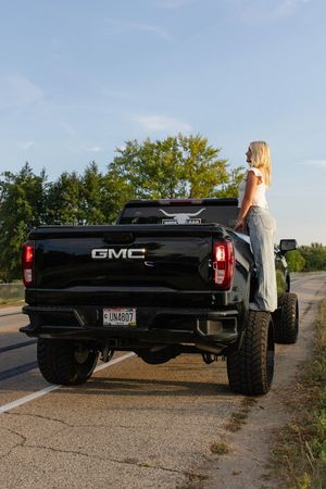 Black GMC pickup truck parked on gravel road during sunset. Senior photo session. Lake Geneva Wisconsin Photographer