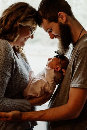 Couple gazing lovingly at their newborn baby in an intimate indoor portrait.