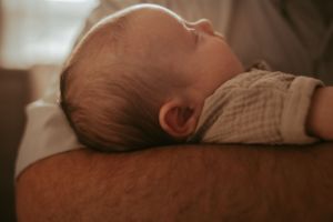 Close-up profile view of a sleeping newborn baby in warm lighting.