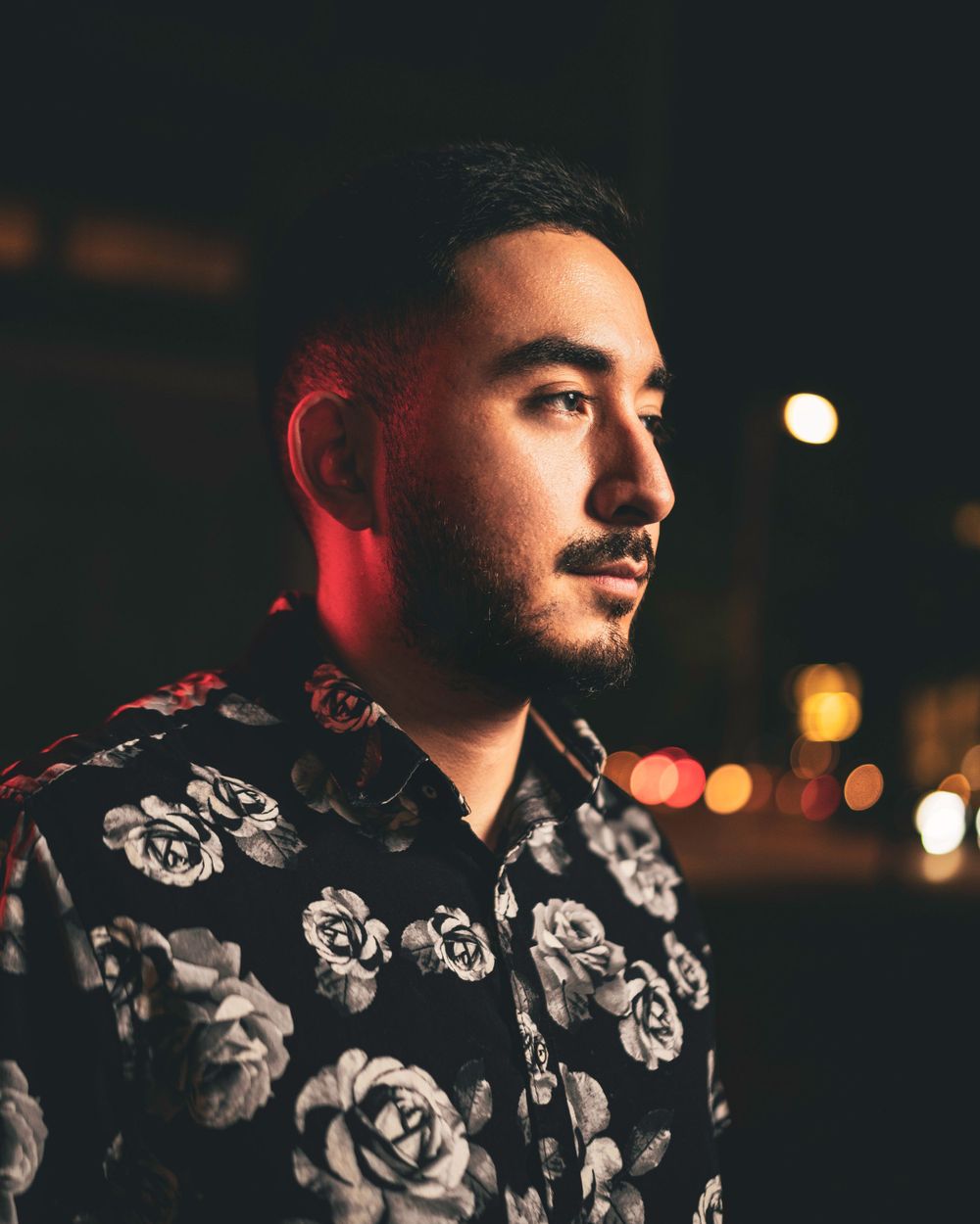 Artistic nighttime portrait with red lighting and floral pattern shirt.