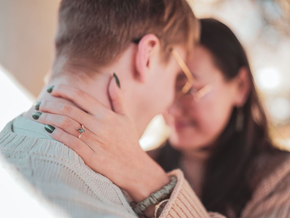 A couple sharing an intimate moment together with hands tenderly placed on neck in soft lighting.