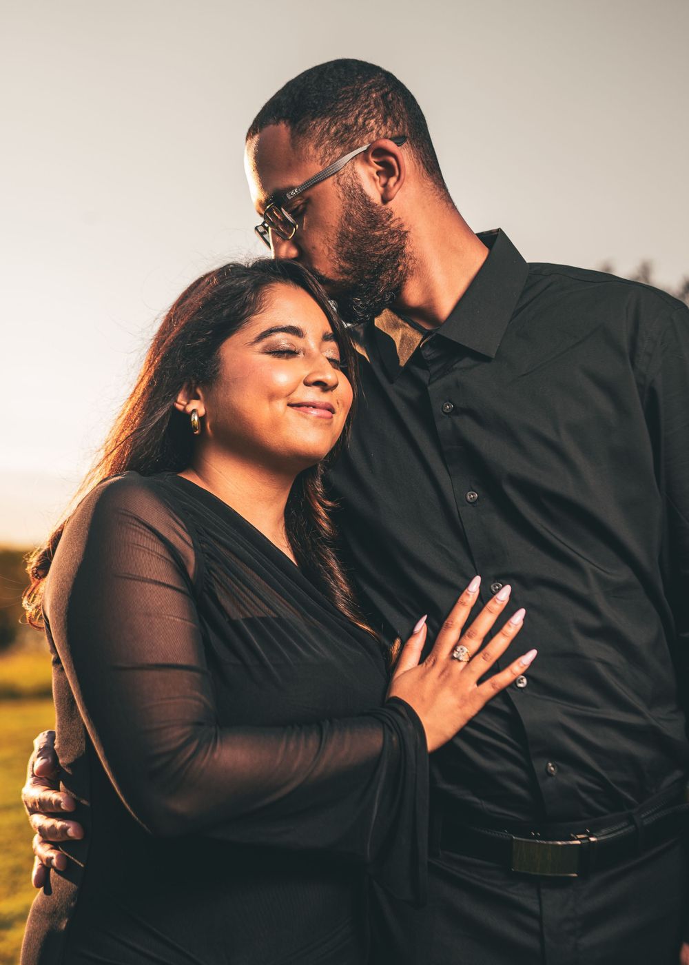 Couple embraces during sunset engagement photo session while showing off ring.