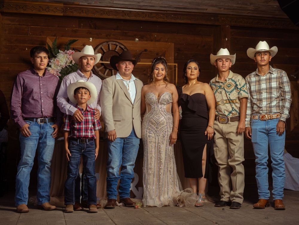 Group photo of western-styled family in formal attire at rustic venue with wooden backdrop.