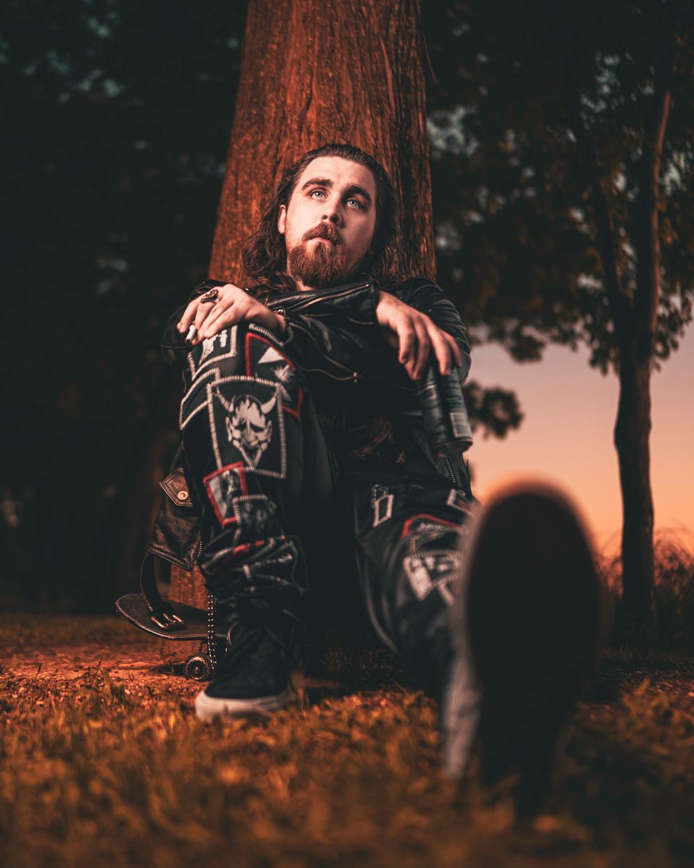 Moody portrait against redwood tree at sunset with dramatic lighting and dark clothing.