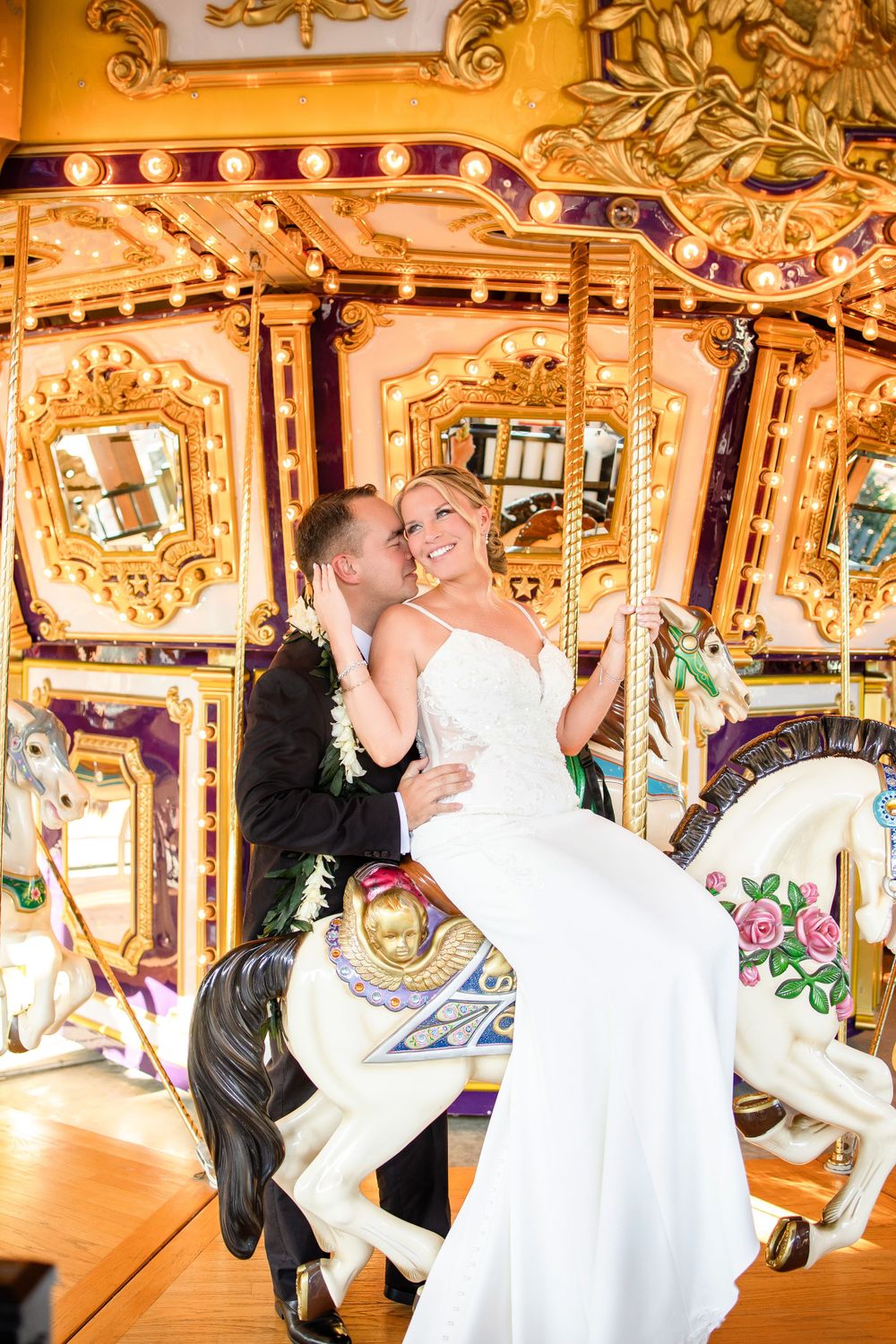 Romantic carousel photo of couple on decorative horse with ornate gold details.