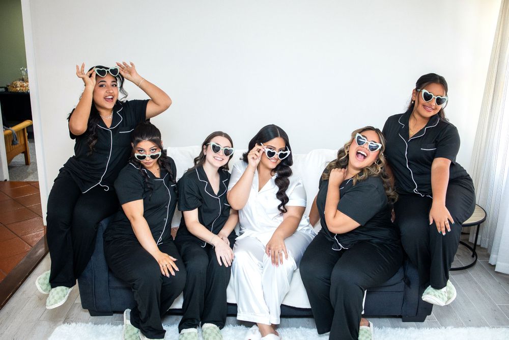 A group wearing matching black outfits poses playfully with sunglasses.