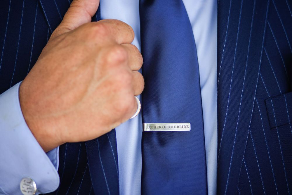 Close-up of a navy pinstripe suit with blue tie and silver tie clip.