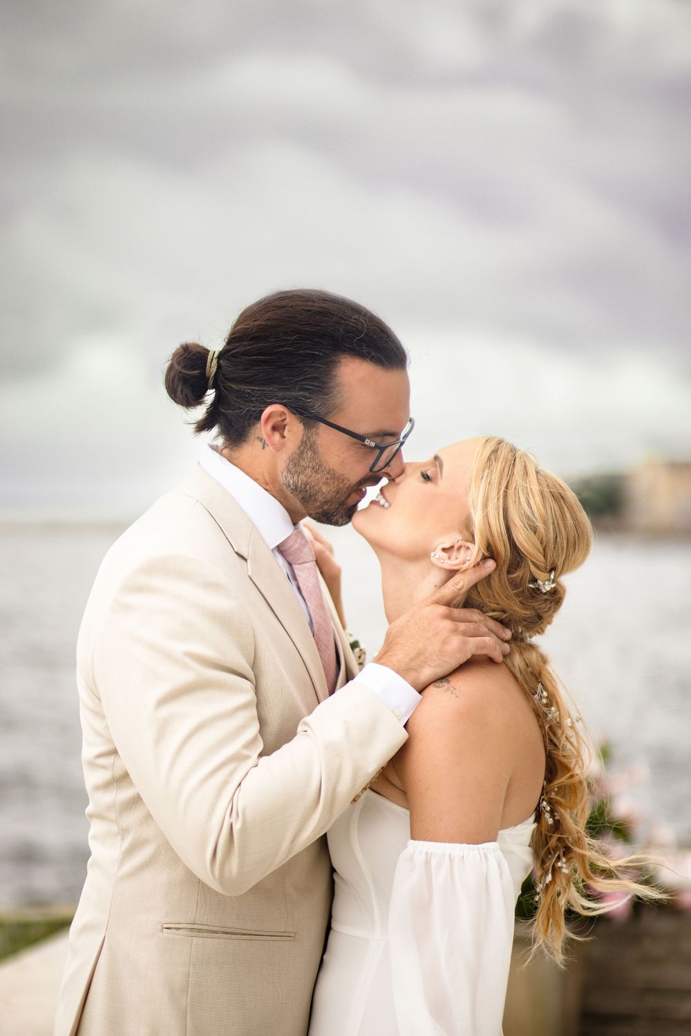 A romantic waterfront moment between a couple in formal attire.