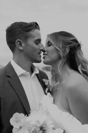A romantic black and white portrait of a couple sharing an intimate moment at their wedding.