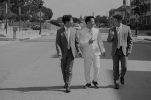 A film strip sequence showing three men walking together on a sidewalk in vintage clothing from the 1950s.