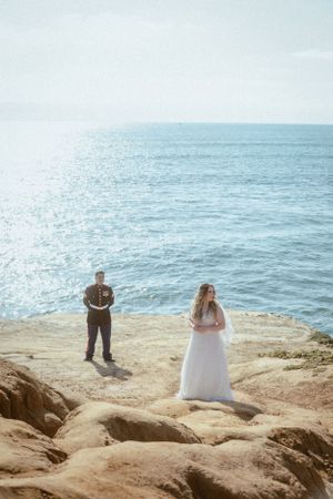 Two people standing on coastal cliffs overlooking the ocean.