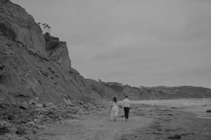 A dramatic coastal landscape with rugged cliffs and beach at sunset.