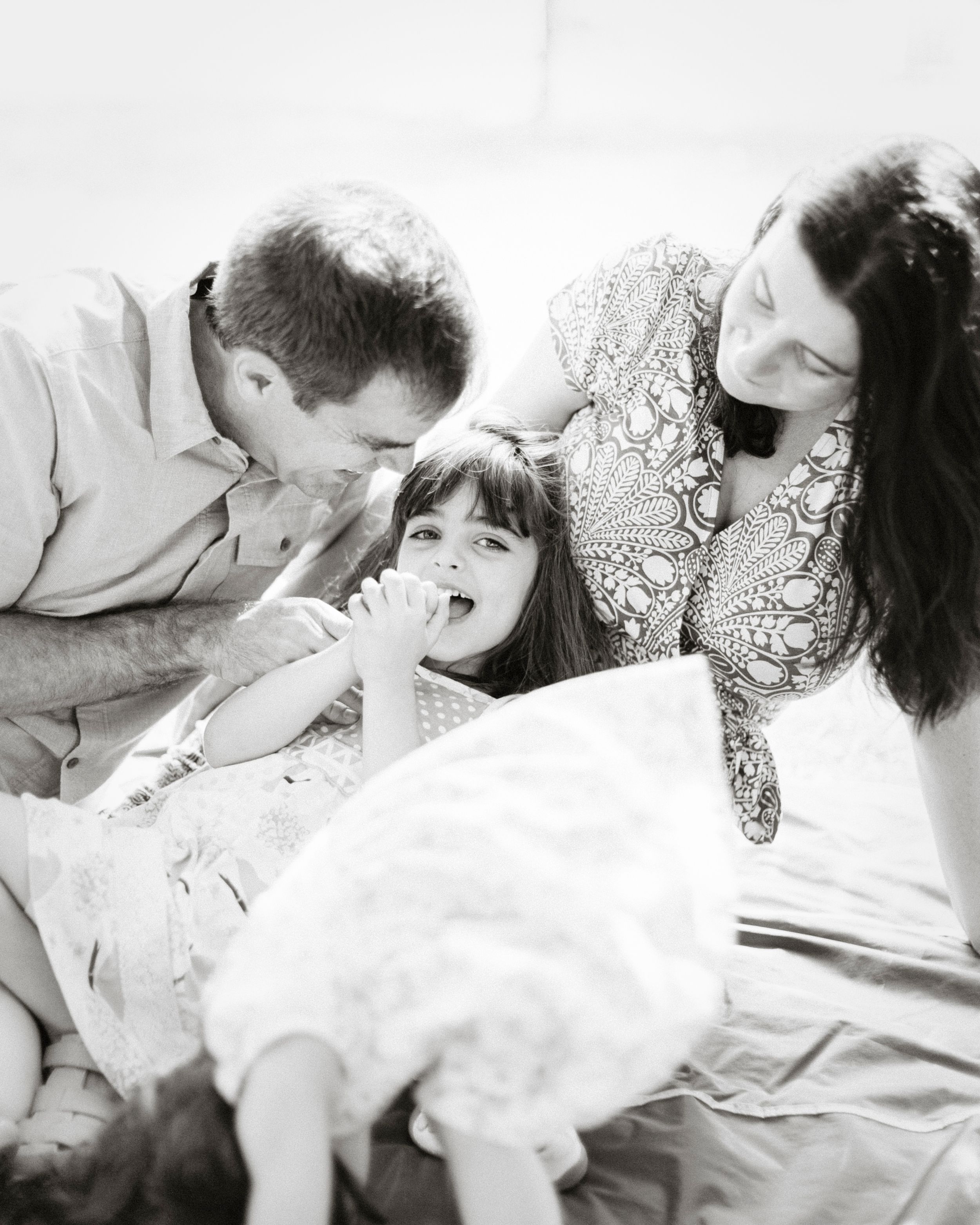 An intimate black and white family portrait showing tender moments of affection on a bed.