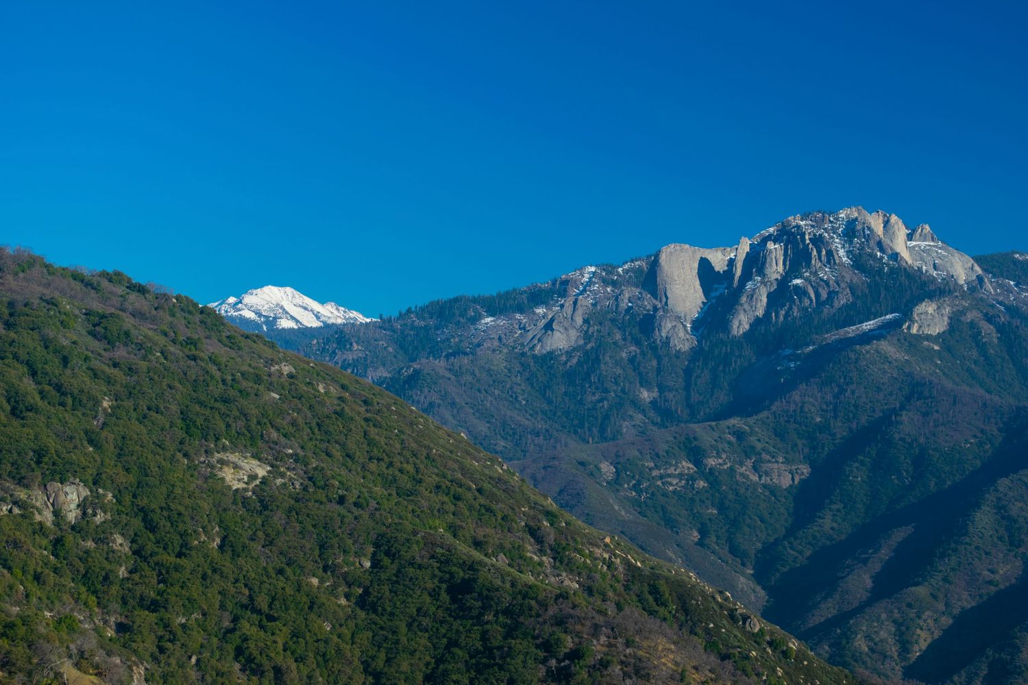 Majestic mountain peaks with snow patches visible through valley in Sequoia National Park.