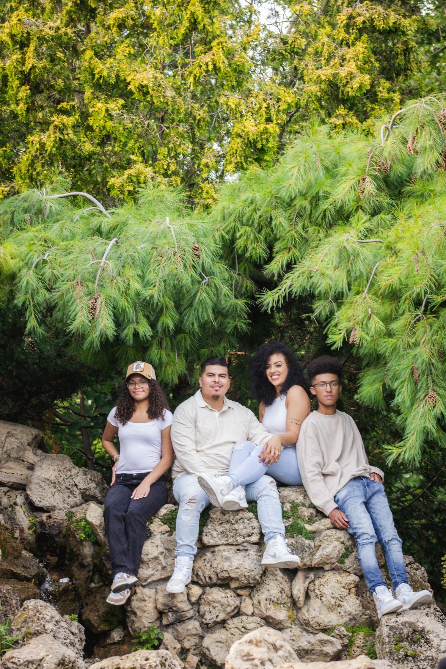 A group relaxes on stone rocks surrounded by lush green foliage in a natural outdoor setting.