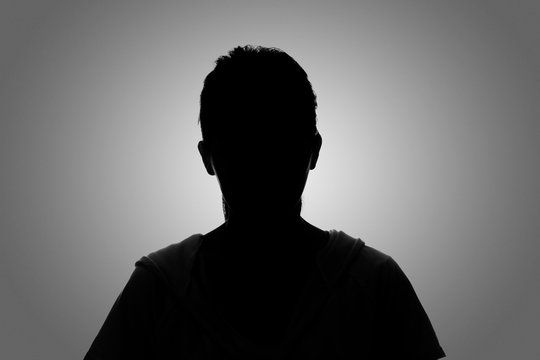 Dramatic black and white silhouette of a man against a gradient grey background.