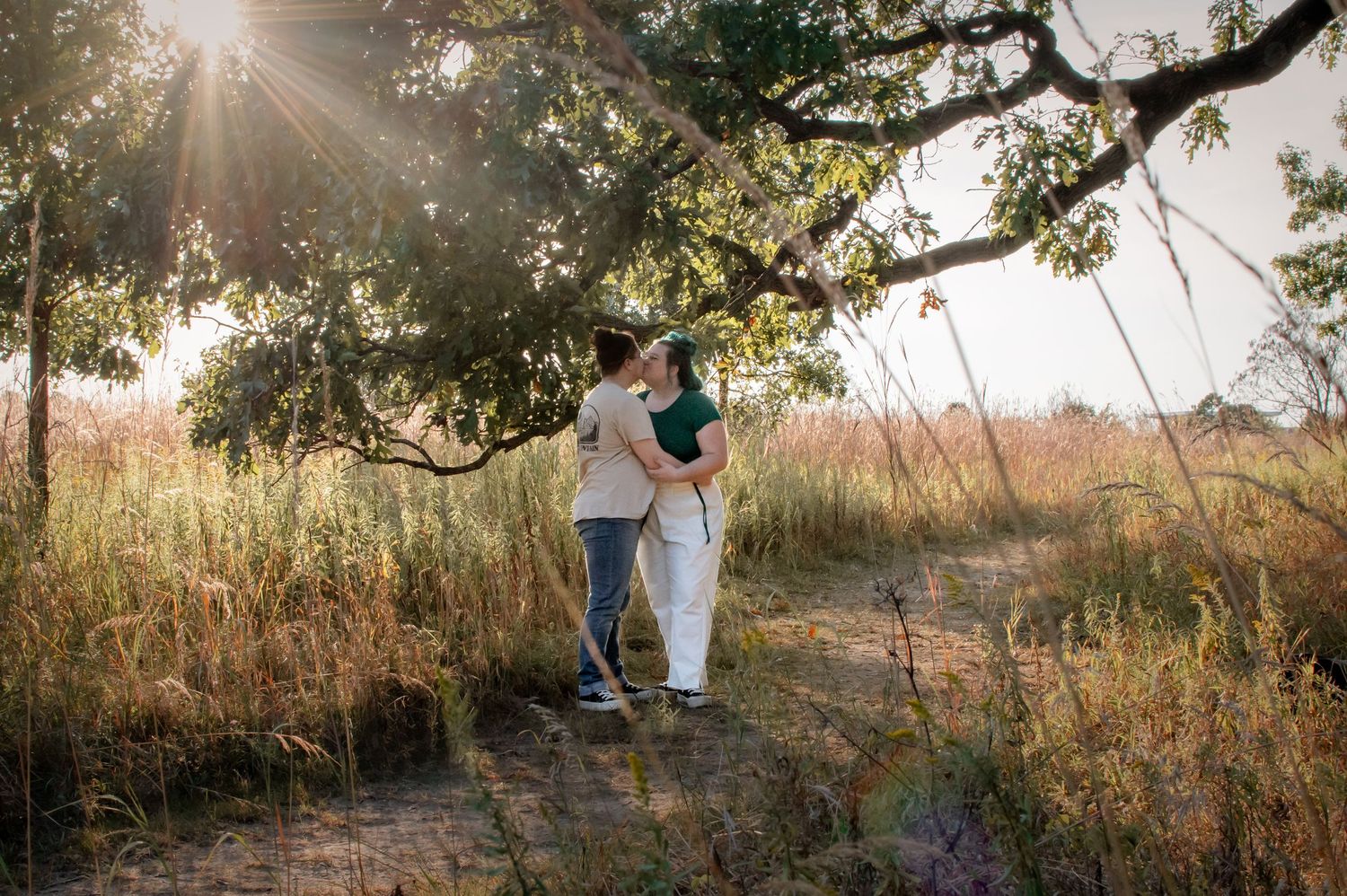 Romantic sunset portrait in golden field with sunburst through oak trees.