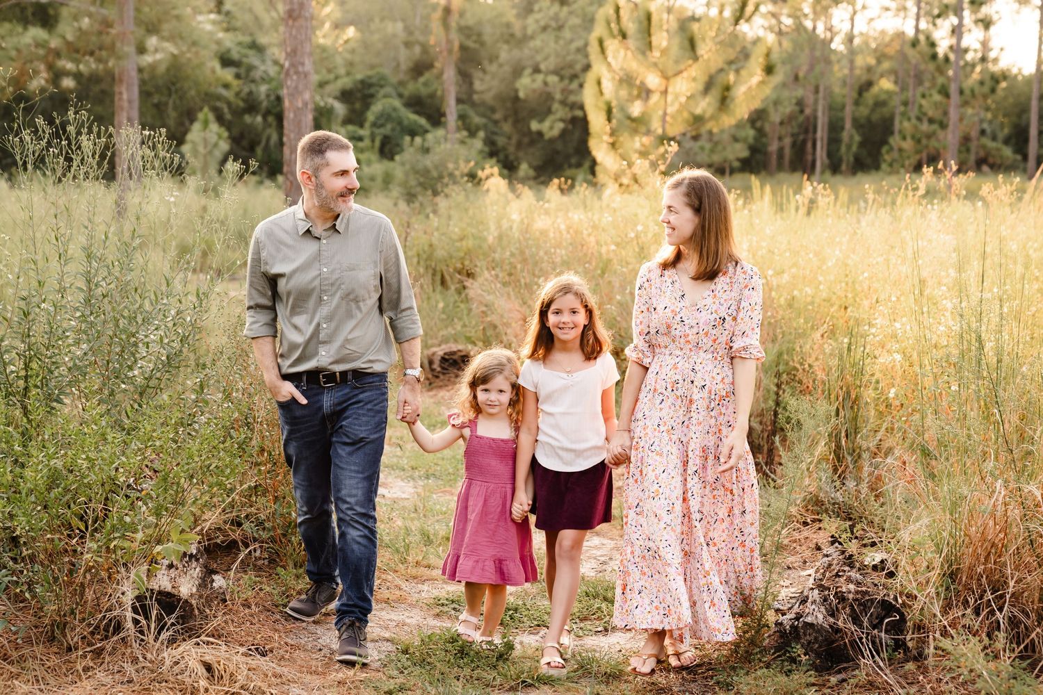 A spring family photo among blooming bluebonnets in a sunny field.